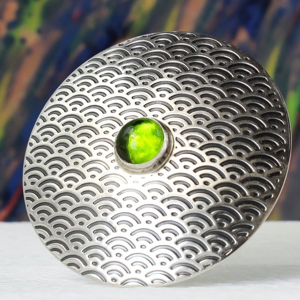 Handmade sterling silver brooch featuring a Japanese fan pattern and a peridot.