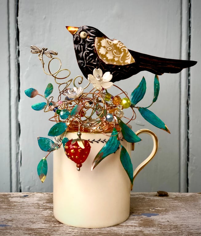 Blackbird sitting in his nest on a small vintage cup
