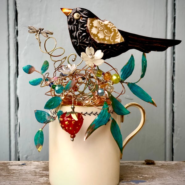 Blackbird sitting in his nest on a small vintage cup