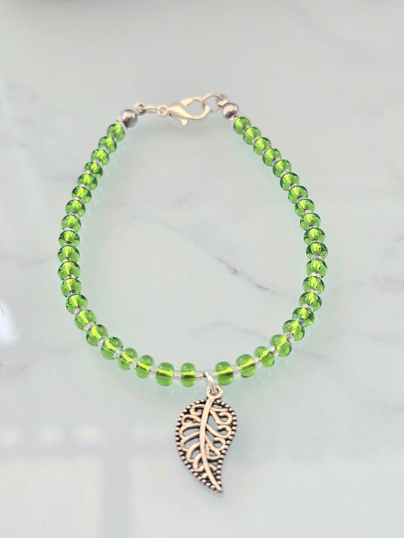 Green beaded bracelet with a silver leaf charm
