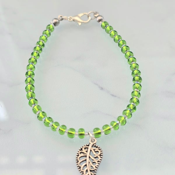 Green beaded bracelet with a silver leaf charm