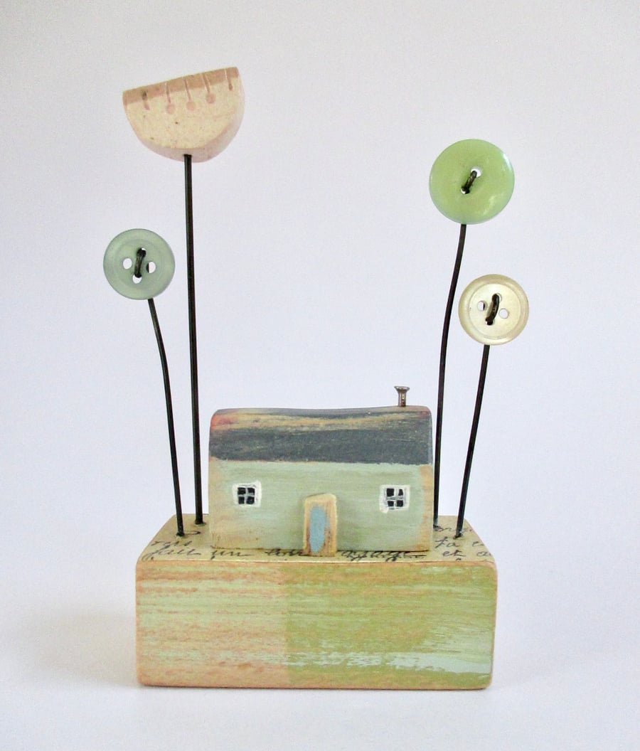 Little wooden painted house with button flower garden