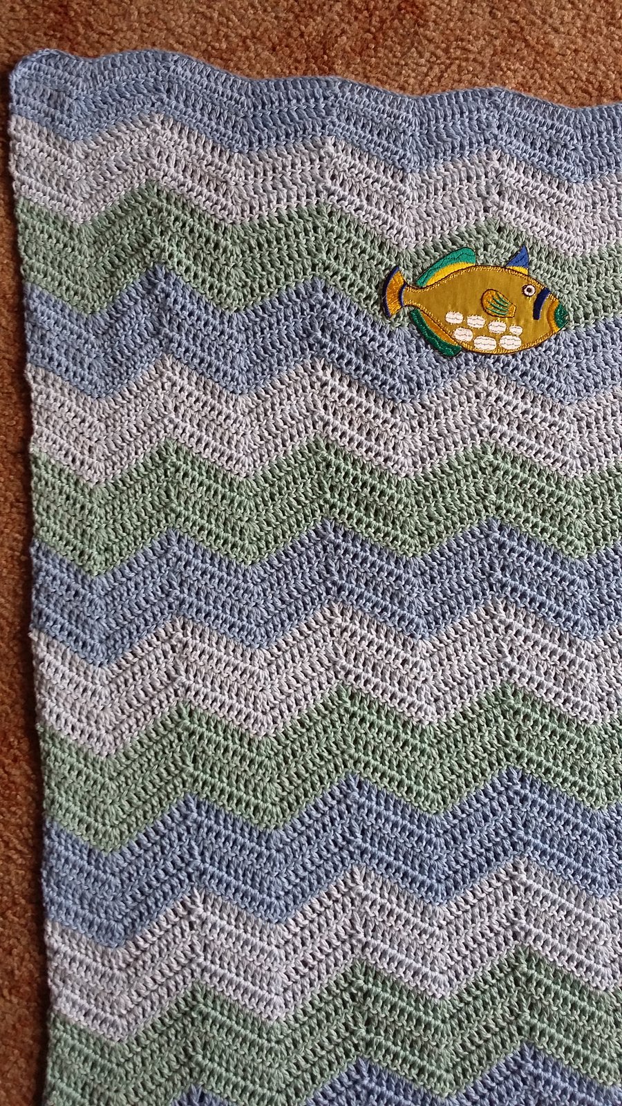 Crochet baby blanket in wavy stripes with applique fish