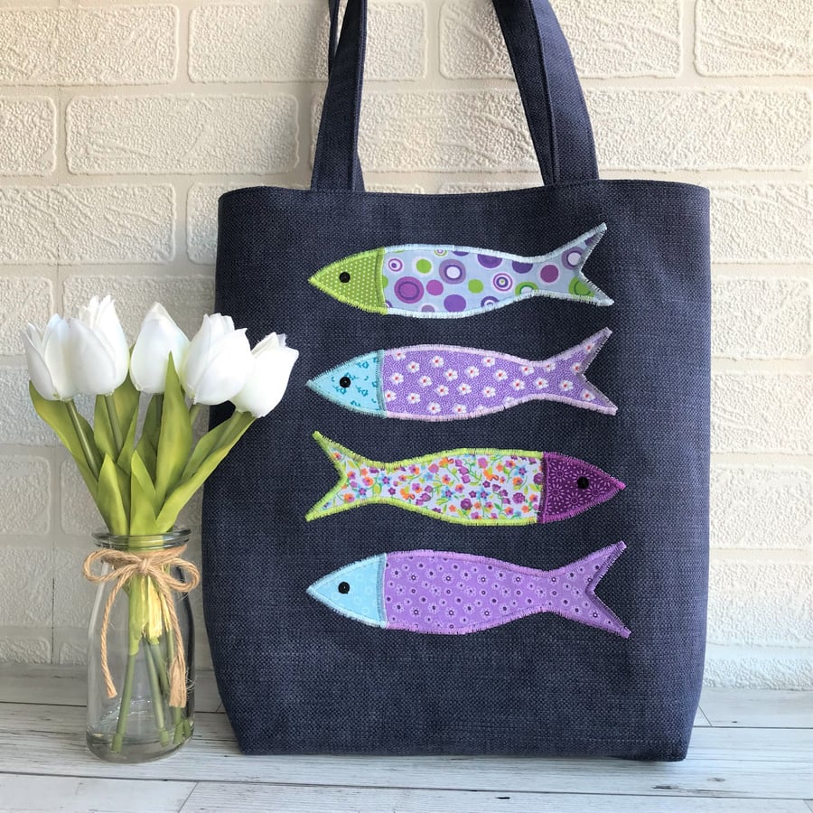 Fish tote bag in dark blue with four colourful fish in purple, blue and green