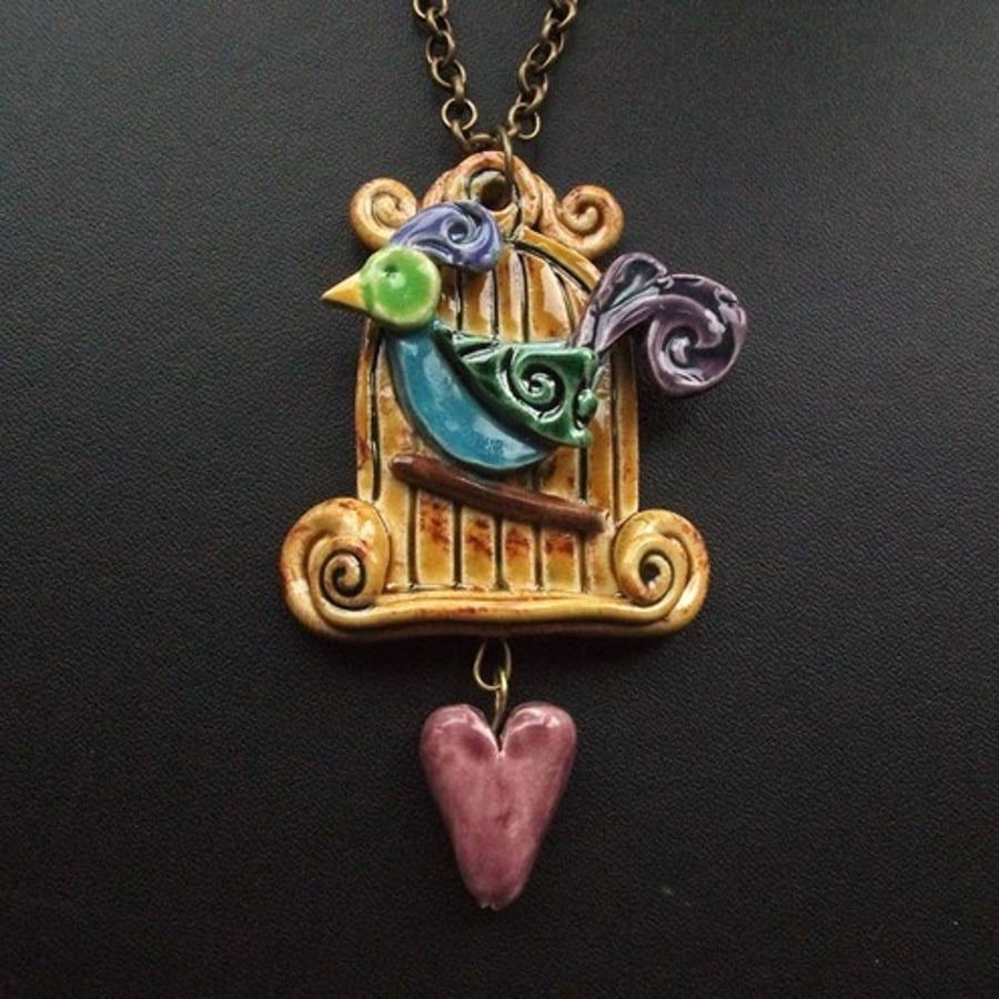 bird in an ornate cage with heart. Ceramic pendant