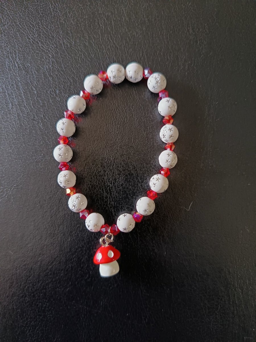 Elasticated cottagecore bracelet with red and white beads and toadstool charm