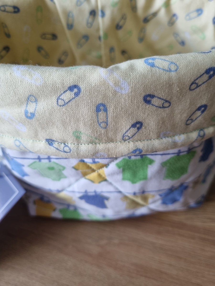 Quilted fabric storage baskets. Baby suits and nappy pins. 