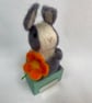Handcrafted needle felted rabbit holding a flower on a wooden box