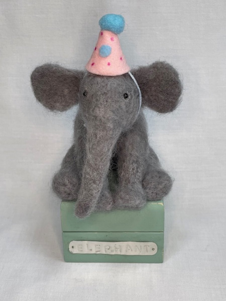 Handcrafted needle felted elephant with removable party hat on a wooden box