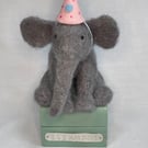 Handcrafted needle felted elephant with removable party hat on a wooden box