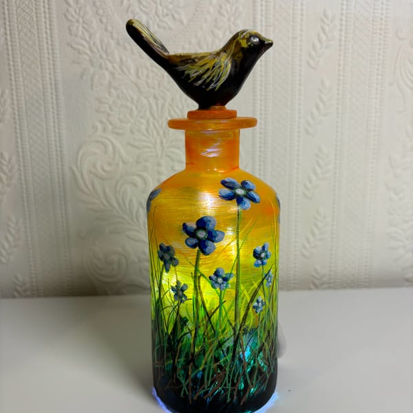 A hand painted and fired glass bottle with glass bird stopper 