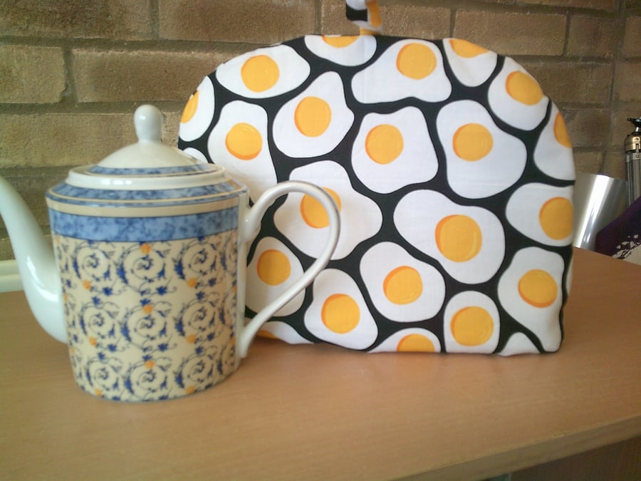 Large Tea  Cosy with Fried Eggs on a Black Background