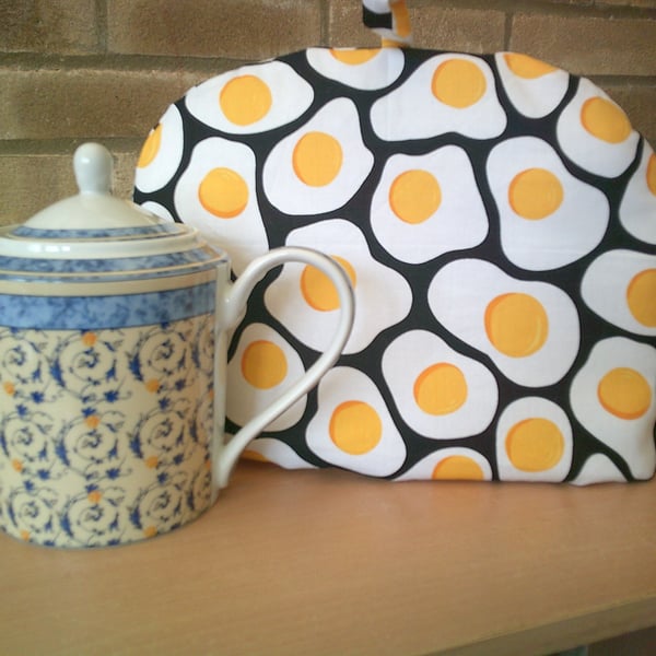 Large Tea  Cosy with Fried Eggs on a Black Background