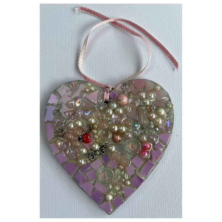 A wooden heart shaped pendant with a mauve theme and glass beads.