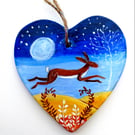 brown hare leaping in moonlight on a ceramic heart 