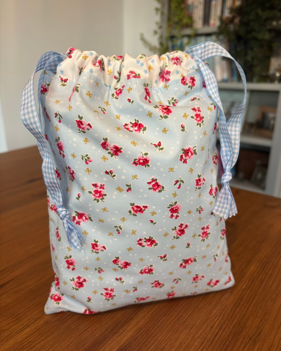 Blue drawstring bag in floral design of pink flowers with gingham ribbon