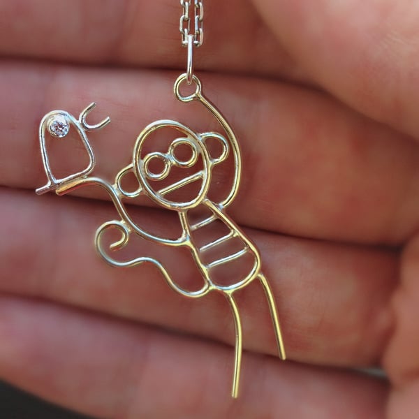 A solid 9ct gold monkey pendant with sterling silver bird 