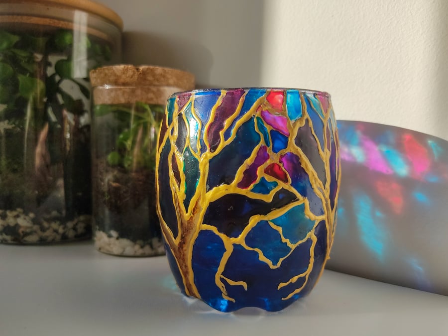 Stained glass effect painted glass candleholder with trees over blue sky