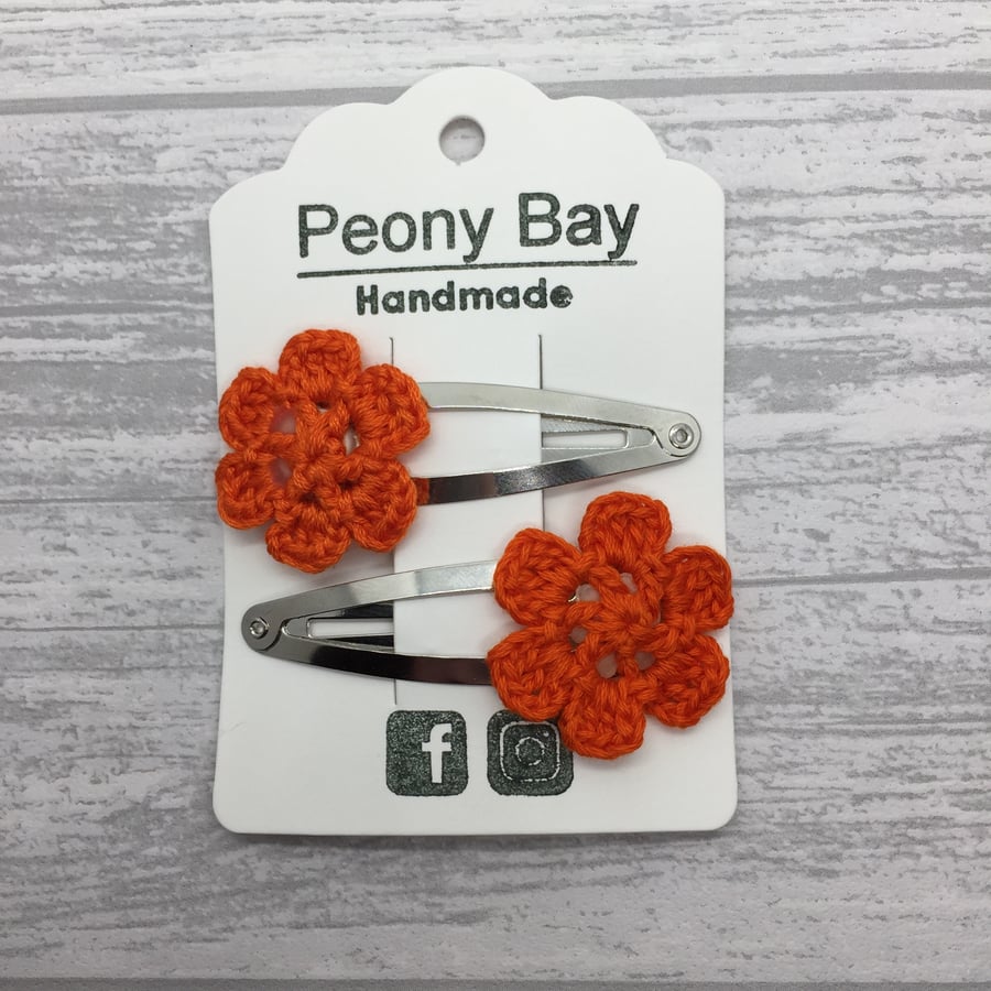 Girl’s hair clips with orange crocheted flowers