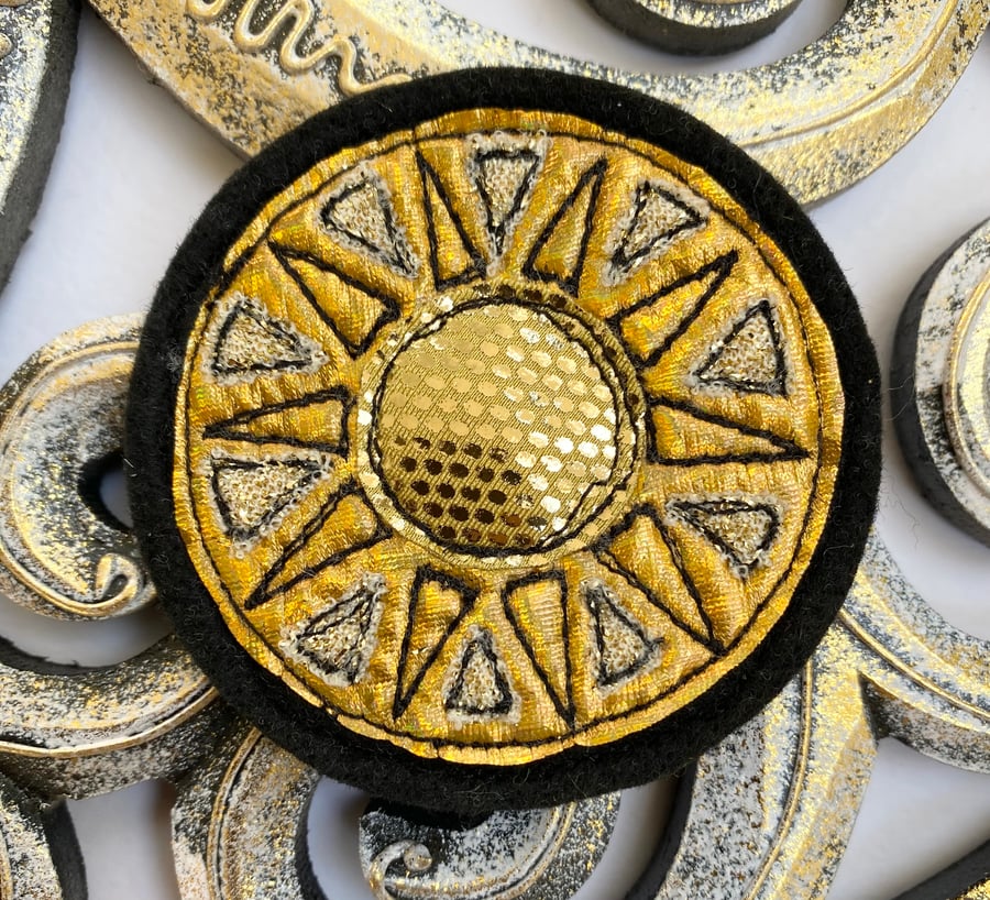 Embroidered gold circular sun brooch pin of badge. 