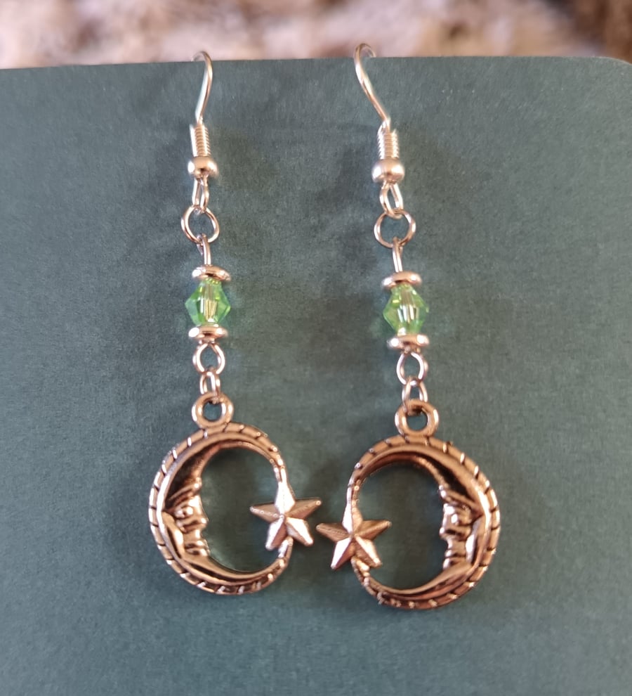 Silver crescent moon dangle earrings with green bead detail