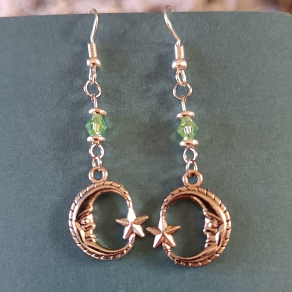 Silver crescent moon dangle earrings with green bead detail