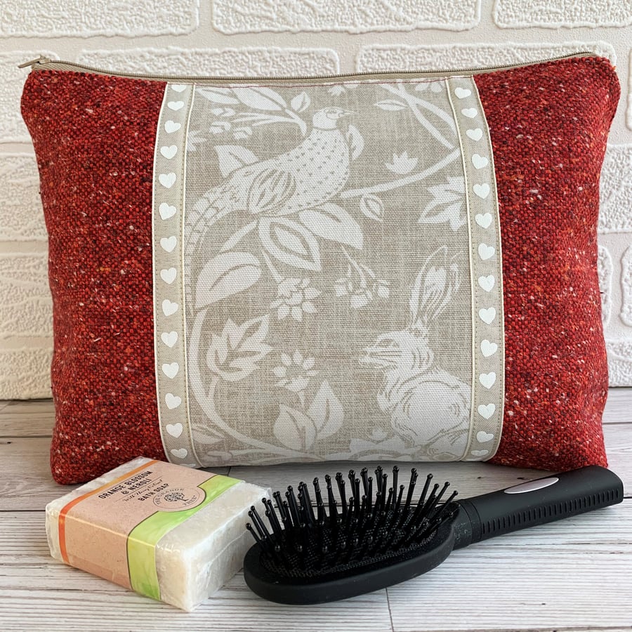 Red toiletry bag with decorative panel featuring a pheasant and hare