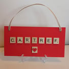 Homemade painted red wooden sign with scrabble tiles spelling Cartref - Home