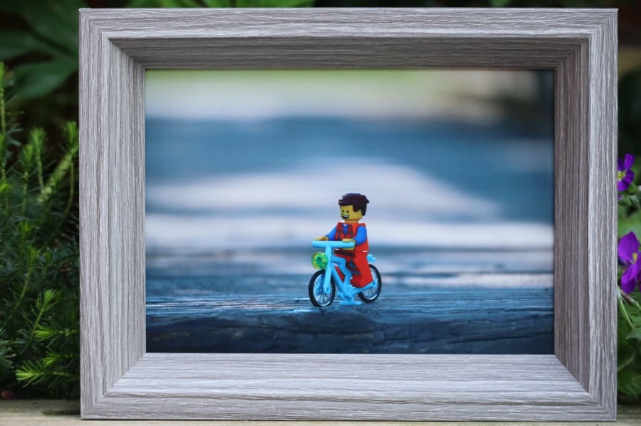 Framed photo of Lego figures. Emmet enjoys a bike ride.
