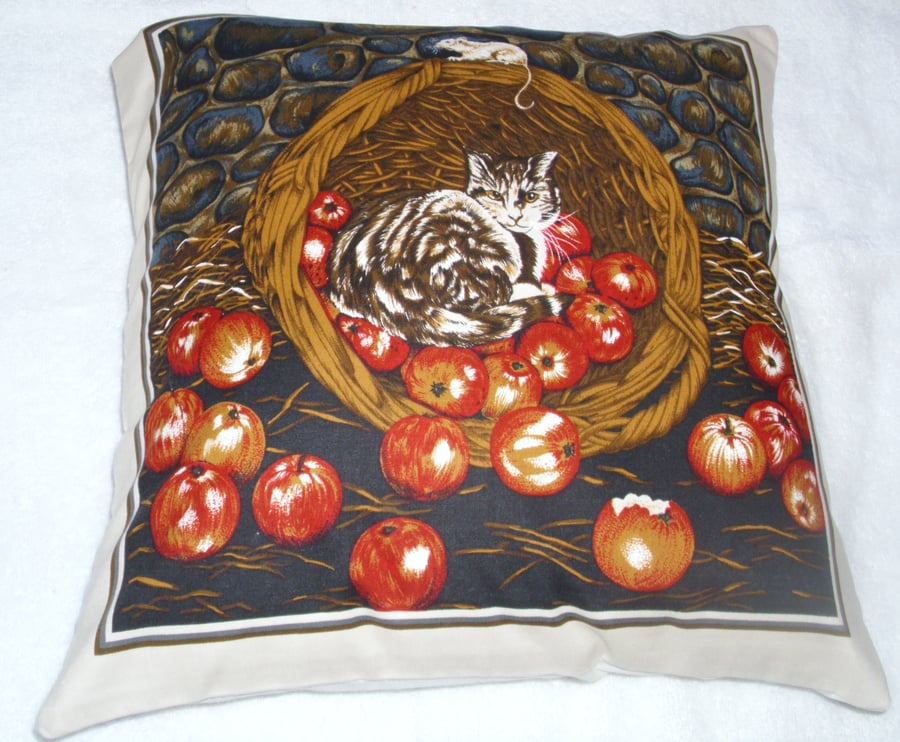 A brown tabby cat in a basket of apples cushion