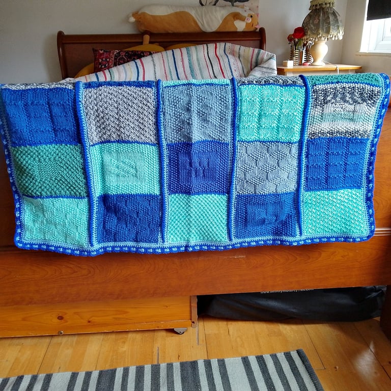 handmade knitted baby or toddler blanket in a blue colourway.