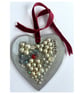 A wooden heart shaped pendant with pearl type and silver coloured shapes.