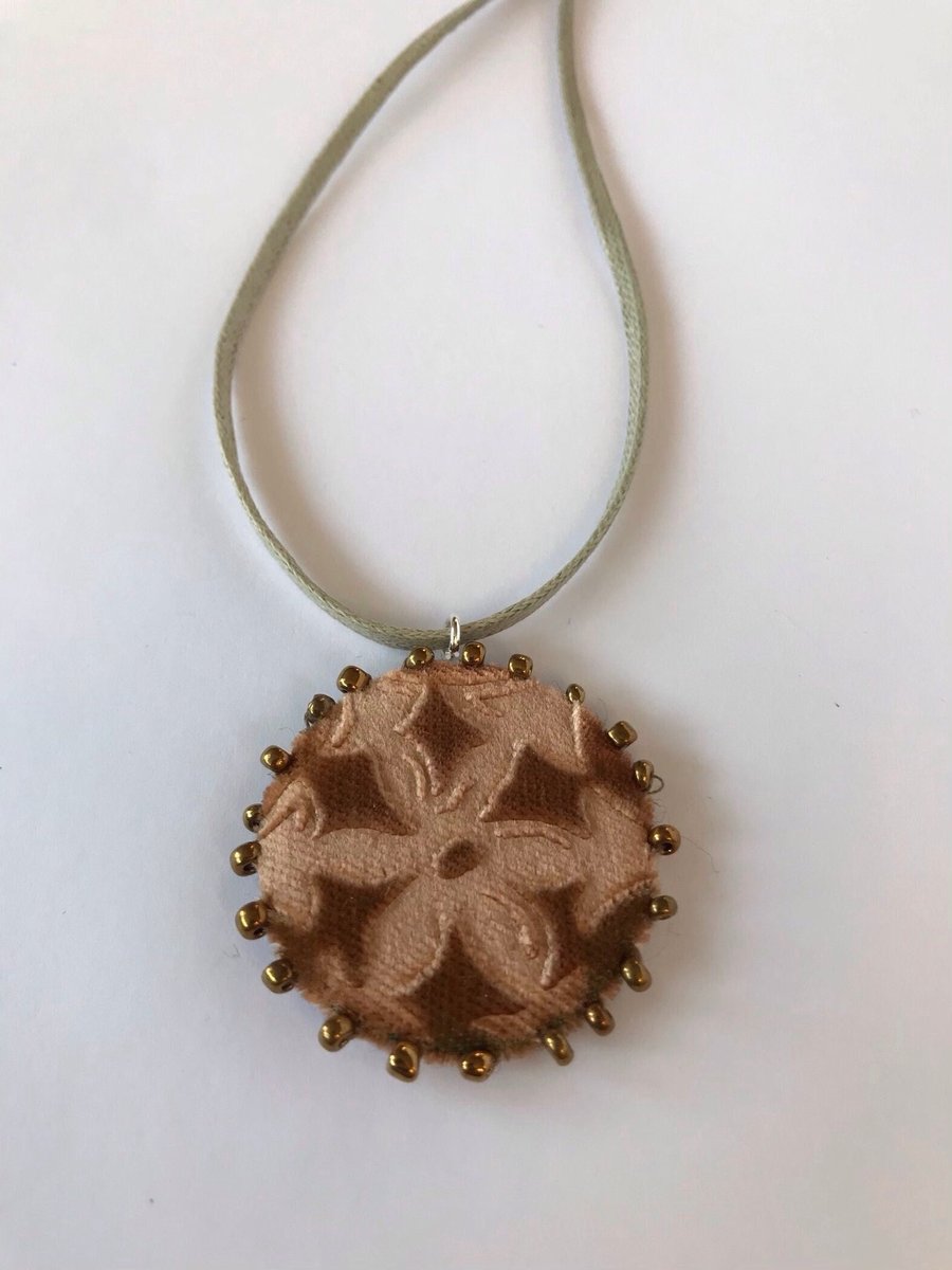 Gold floral pendant necklace with beaded and embossed velvet design.