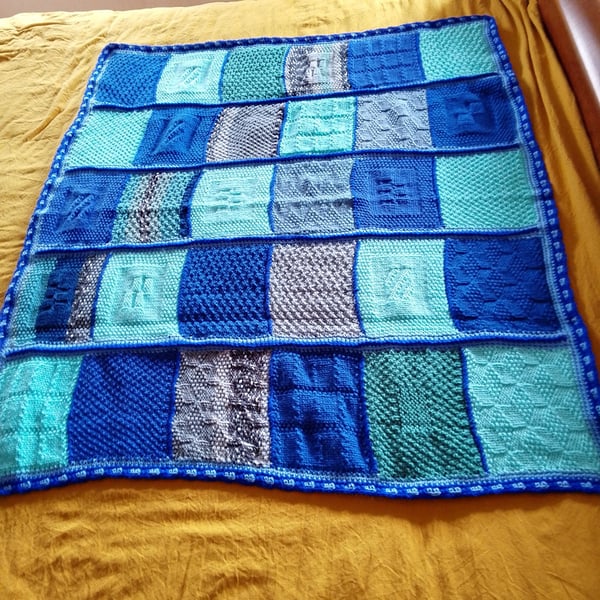handmade knitted baby or toddler blanket in a blue colourway.