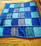 handmade knitted baby or toddler blanket in a blue colourway.