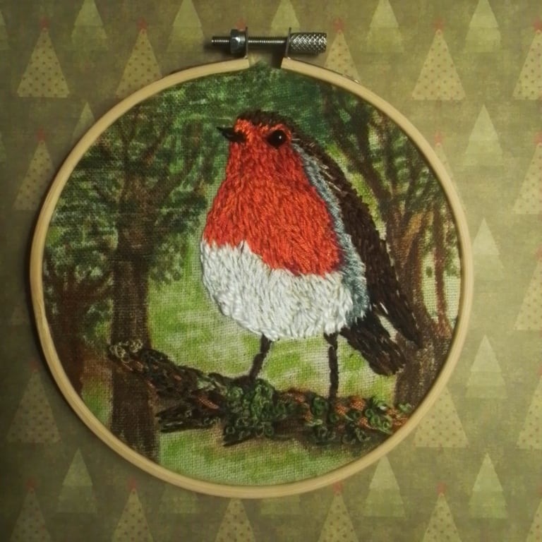 Embroidered robin in woodland .