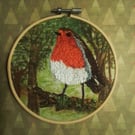 Embroidered robin in woodland .
