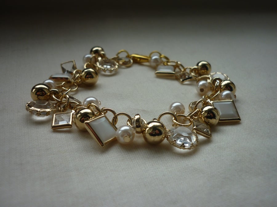 GOLD, CRYSTAL AND PEARL FANCY CHARM BRACELET.  1107