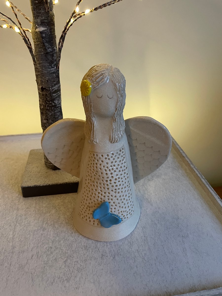 Angel sculpture with blue butterfly & yellow flower