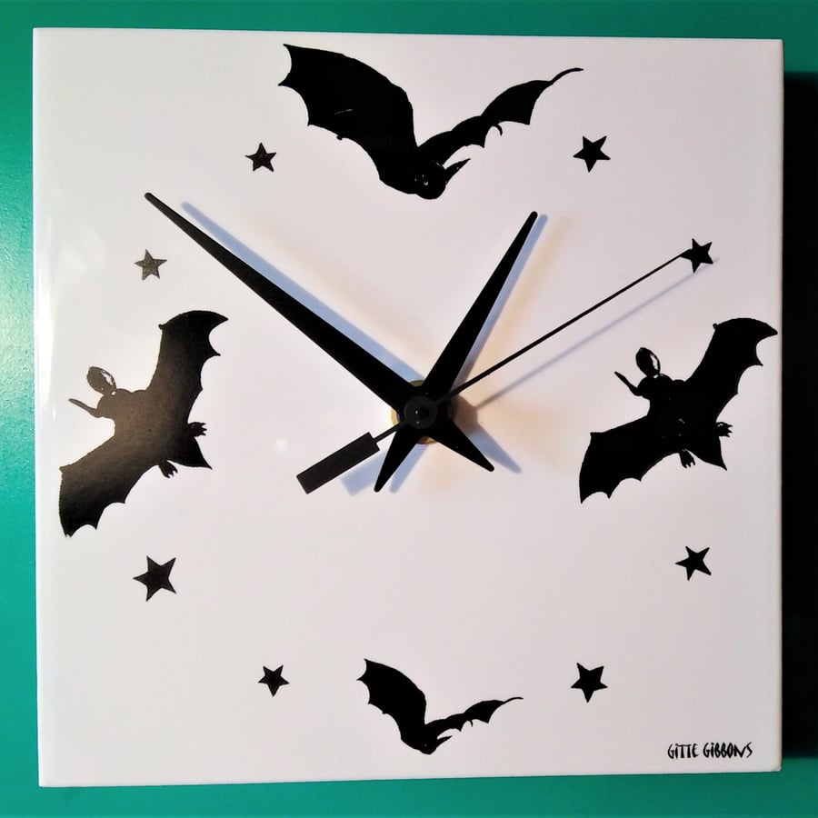 A bat tile wall clock decorated with black flying bats and powered by a quarts b