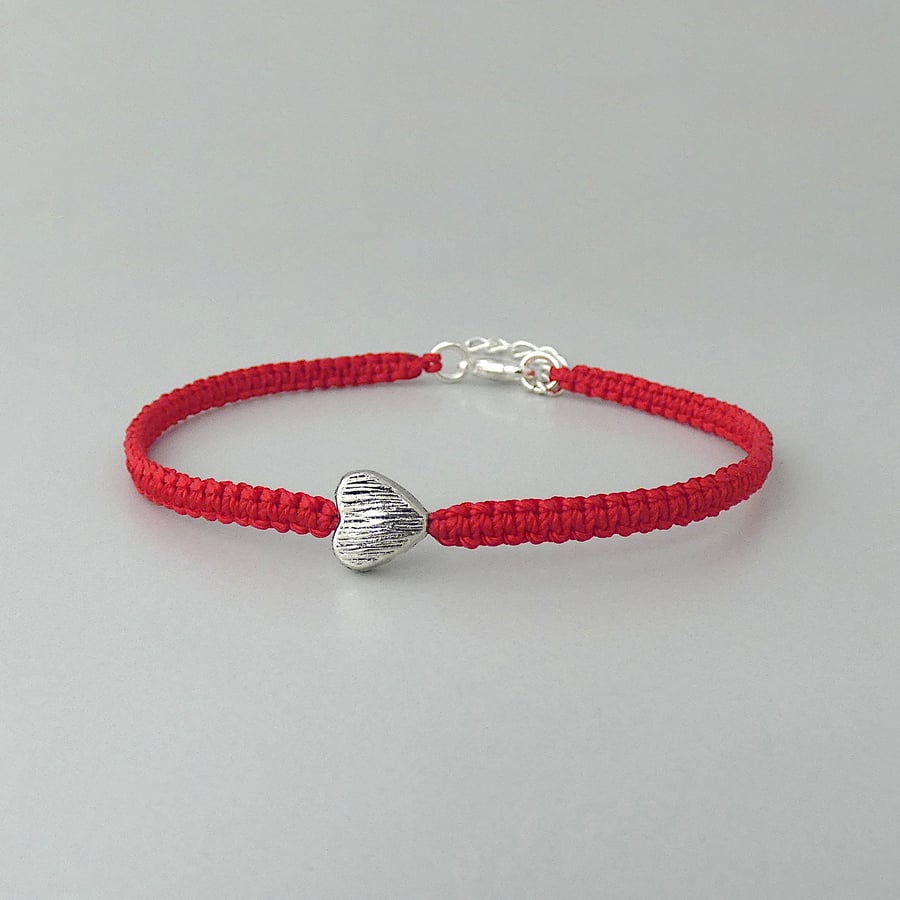Red 7" macramé bracelet with silver plated heart charm and 1” extender chain.