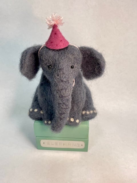 Handcrafted needle felted elephant with removable party hat on a wooden box