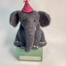 Handcrafted needle felted elephant with removable party hat on a wooden box