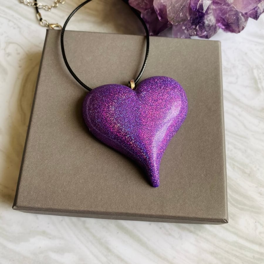 Purple sparkly statement polymer clay heart pendant on a black cord necklace.