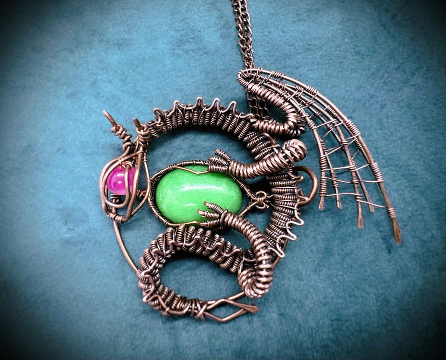 Antique copper wire wrapped dragon pendant clutching an egg