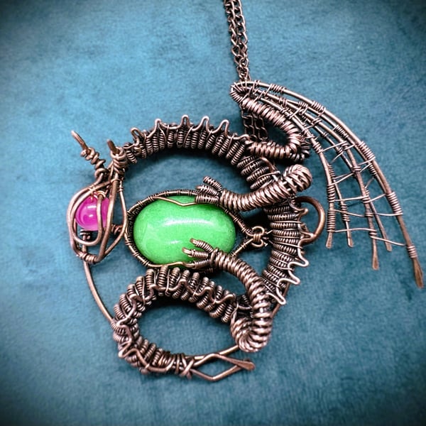 Antique copper wire wrapped dragon pendant clutching an egg