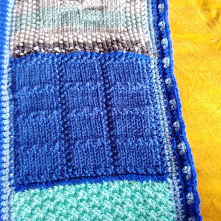 handmade knitted baby or toddler blanket in a blue colourway.