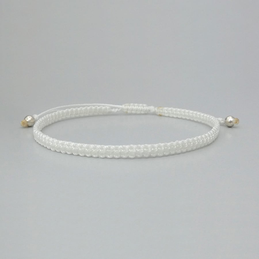 White macramé bracelet with silver plated bead ends. Extends from 7” to 9.5”.