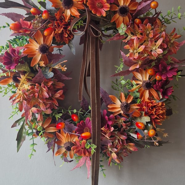 Lush autumn wreath with orange Hydrangea, Orange red berries, maple leaves.