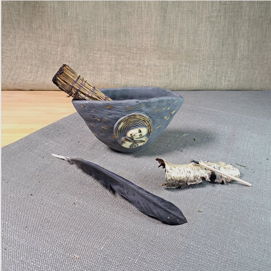 A bowl for smudging and plant arrangements featuring a hand carved relief medal